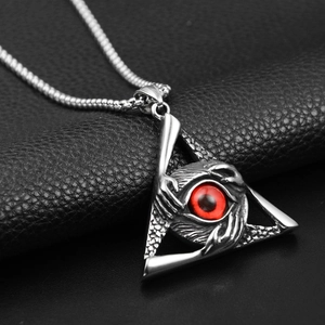 Macro detail of gothic triangle pendant with red evil eye and silver box chain