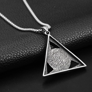 Macro shot of silver stainless steel triforce pendant with brushed texture on black leather