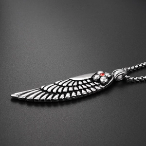 Macro shot of vintage steel feather pendant with red gemstone detail and box chain