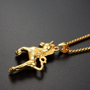Macro shot of gold-plated flying unicorn pendant with intricate spiral horn and mane details