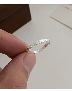 Close-up of minimalist silver ring featuring textured square lava pattern and sleek design