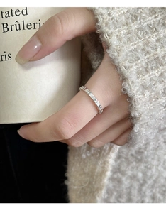 Close-up of minimalist silver geometric texture ring worn against a cozy aesthetic background