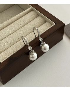 Close-up of pearl drop earrings with flower metal caps and pavé stones in a jewelry box