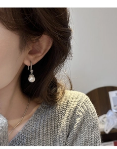 Close-up of French pearl drop earrings with sparkling zircon on a female model