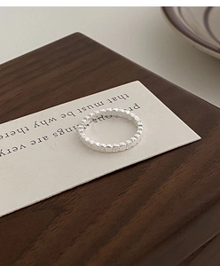 Macro shot of silver minimalist lava texture beaded ring on white decorative card