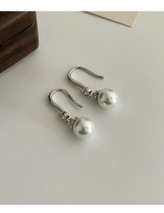 Macro detail of French pearl drop earrings with micro-inlaid cubic zirconia on silver hooks