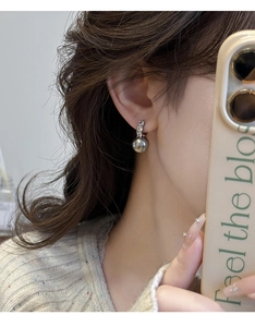 Détail de boucles d'oreilles en perles grises et créoles en argent sur le mannequin