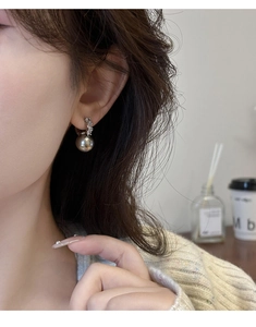 Gros plan sur boucle d'oreille en perle grise avec monture en argent sertie de diamants