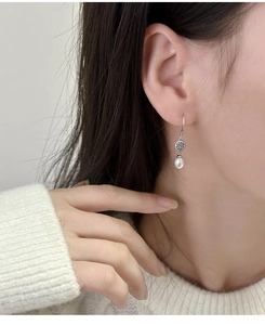 Primo piano di orecchini a goccia con perla e argento indossati da una modella