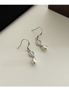 Dettaglio degli orecchini con perle a goccia e motivi traforati circolari in argento
