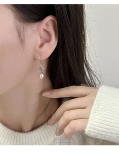 Dettaglio di orecchini vintage in argento con perle a goccia indossati da modella