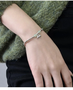 Close-up of bamboo-style silver bracelet with green jade beads and small bell charms
