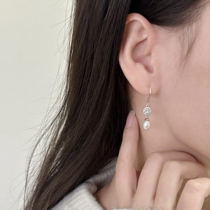 Eleganti orecchini con perle a goccia in argento con motivi geometrici su una modella