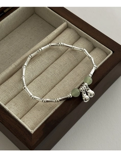 Detailed shot of bamboo style silver bracelet with green jade beads and small bells