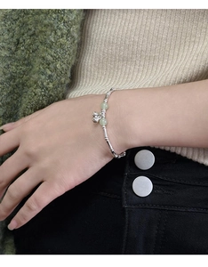 Detailed view of silver bamboo joint bracelet with green jade beads and bell charm