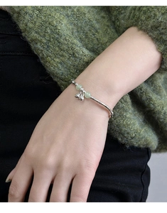 Close-up of bamboo-style silver bracelet with green beads and bells on a model wrist