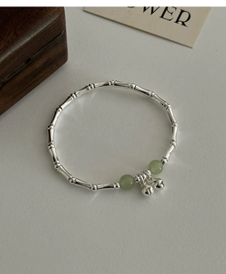 Detail of silver bamboo joint bracelet with green jade beads and small charms