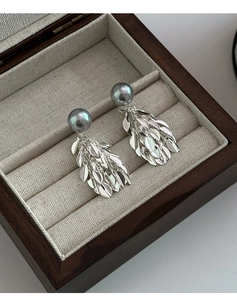 Détail macro de longues boucles d'oreilles à pompons argentés avec perles grises