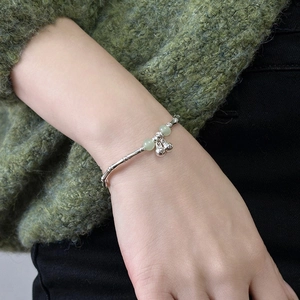 Bamboo style silver bracelet with green beads and double bells on a model wrist