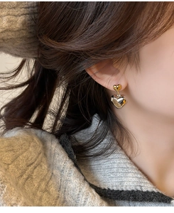 Gros plan détaillé de boucles d'oreilles pendantes double cœur portées sur l'oreille