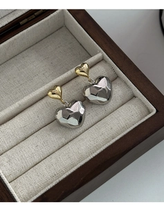 Détail de boucles d'oreilles cœur bicolores avec haut doré et cœur argenté en boîte