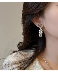 Gros plan macro sur des boucles d'oreilles ailes à franges et perles grises