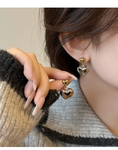 Détail de boucles d'oreilles cœur bicolores avec clous dorés et cœurs facettés argent