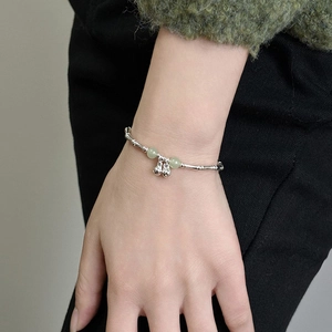 Bamboo-style silver bracelet with green jade beads and double gourd charms on wrist
