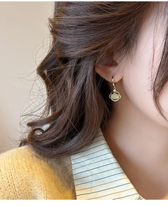 Gros plan de boucles d'oreilles Ruyi dorées avec opale et zircons sur un mannequin