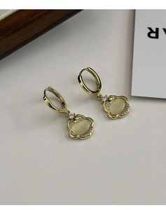 Détail de boucles d'oreilles dorées avec pierre œil de chat et zircons incrustés