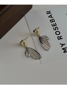 Detail of minimalist heart wing earrings with golden heart studs and silver textured fans