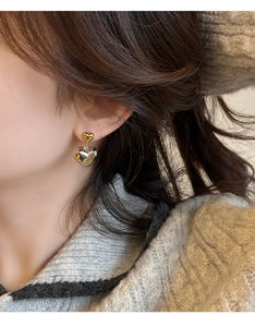 Gros plan de boucles d'oreilles en forme de cœur bicolores or et argent sur l'oreille