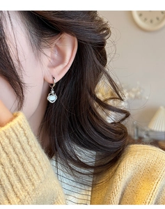 Détail de boucles d'oreilles élégantes en pierre œil de chat portées par un mannequin chic