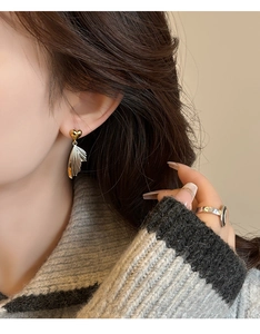 Close-up of elegant gold heart wing earrings and minimalist silver ring on model