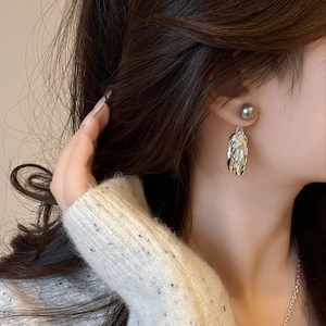 Boucles d'oreilles élégantes en perles en forme d'ailes portées par un mannequin