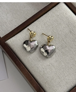 Gros plan de boucles d'oreilles cœur bicolores avec clous dorés et pendentifs en argent martelé