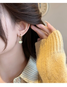Gros plan d'une boucle d'oreille Ruyi en or avec pierre d'opale portée pour un style vintage