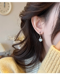 Détail d'une boucle d'oreille créole en argent avec pierre œil de chat sur modèle