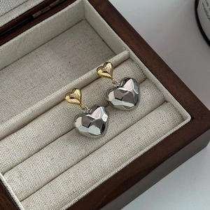 Boucles d'oreilles double cœur élégantes avec facettes géométriques or et argent sur coffret