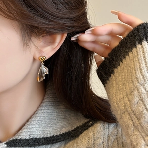 French vintage heart and silver wing fan drop earrings on model with knit sweater