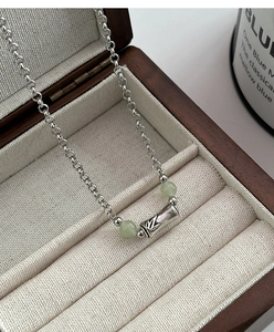 Close-up of bamboo-shaped pendant with silver texture and light green jade beads