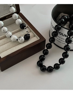 Detail van kralenkettingen met zwarte onyx en witte turkoois kralen en metalen sluitingen