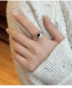 Gros plan d'une bague argentée avec onyx noir, portée sur un pull en maille confortable