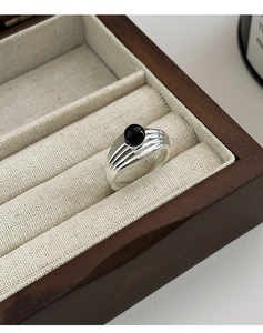 Détail de la bague texturée argentée avec onyx noir sur fond en lin beige naturel