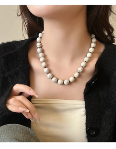 Detail van witte turkoois kralen met marmerpatroon aan een zwarte koordketting