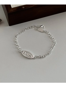 Gros plan détaillé d'un bracelet à maillons argenté doté d'un charm lettre LOVEME évidé