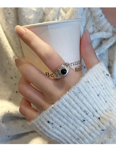 Détail d'une bague vintage en argent avec onyx noir sur une texture métallique plissée