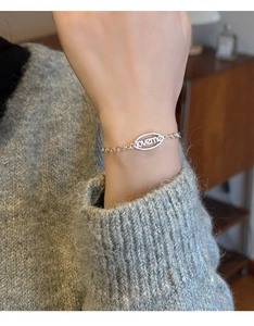 Gros plan détaillé du pendentif ovale Loveme sur un bracelet en chaîne dorée minimaliste