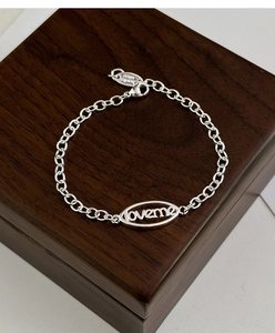 Gros plan d'un bracelet en argent avec plaque ovale ajourée gravée du mot LOVEME
