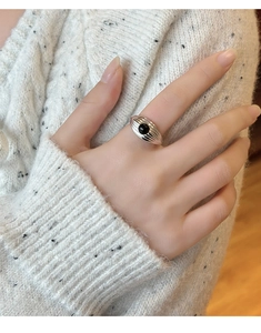 Gros plan d'une bague vintage en argent avec onyx noir et texture lignée sur le doigt